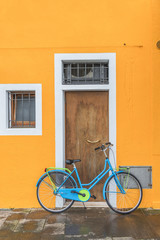 Blue bicycle in front of yellow wall and door, Venice