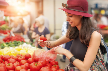 A young woman buying fruits and vegetables at a weekly market. Healthy diet