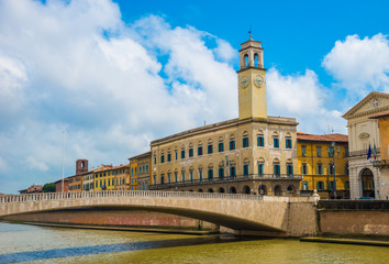 Traditional house architecture of Pisa town, reflected in the river, among a bridge, in Italy