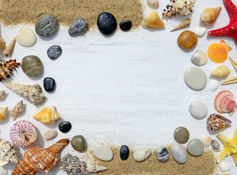 Beach sand, pebbles, sea shells and starfish on a white wooden background