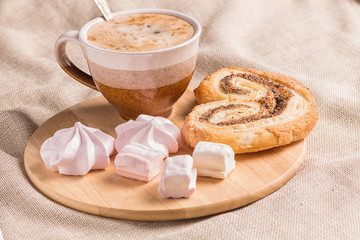 sweet buns, meringues and coffee cup on a wooden board