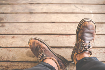 Top view of Male feet in old leather shoes on wood