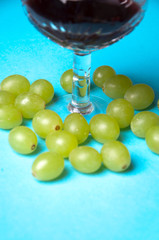 glass of wine and grapes, isolated on blue