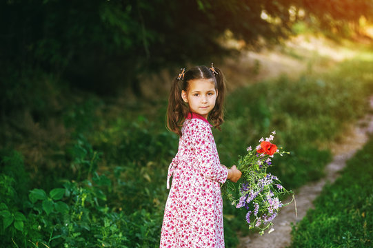 Beautiful little girl with wildflowers in the Park