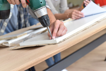 Closeup of electric drill assembling furniture pieces