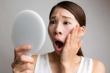 鏡を見て驚く女性
