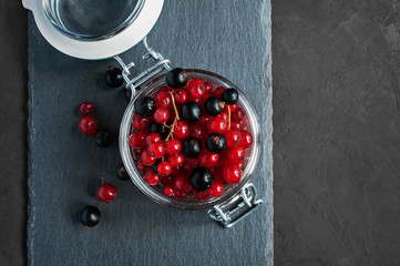 Red and black currants in a glass jar