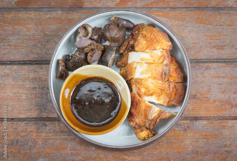 Wall mural fried chicken and entrails on a white plate set on a wood table