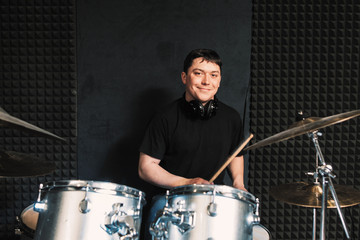 Smiling drummer plays on drum set. Playing on drums musician loks at camera and smiles. Smiling...