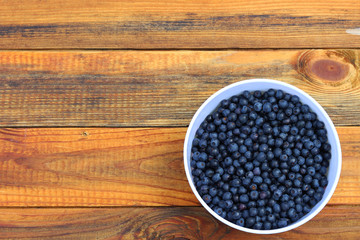 bilberryes in bowl on wooden background