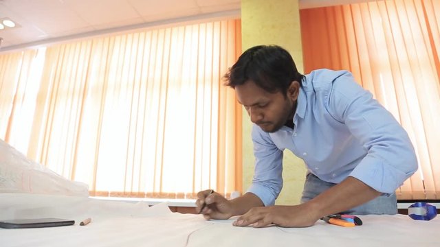 Indian engineer designer drafting draw on a table in a bright room. 
