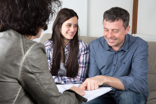 Smiling couple signing financial contract at home