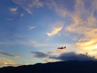 Fototapeta na wymiar flying airplane over mountain range at sunset