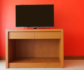 Flatpanel tv on wooden cabinet against orange wall
