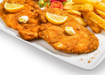 fried fish in breadcrumbs with potatoes fries and vegetables