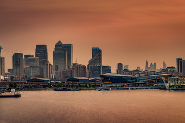 The London skyline at sunset with the skyscrapers from The City of London ( London’s financial center) and the skyline of Canary Wharf ( Isle of Dogs, Docklands)