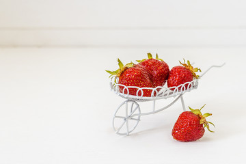 Ripe strawberries in a decorative garden trolley on a white back