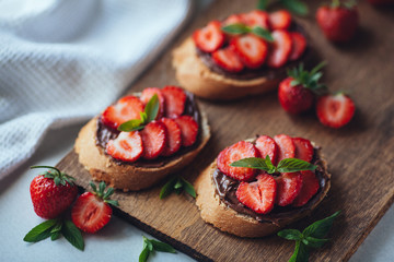 Fototapeta na wymiar Strawberry bruschetta with chocolate paste and mint.Healthy thre