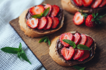 Strawberry bruschetta with chocolate paste and mint.Healthy thre