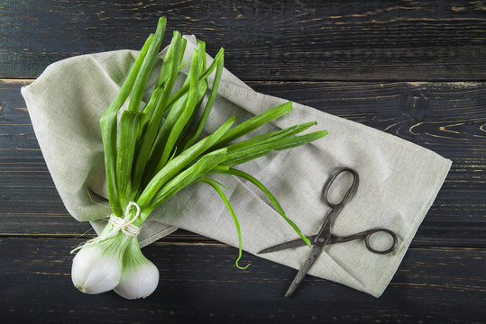 Cebollas de primavera o cebolletas tiernas en un manojo sobre un fondo de madera 