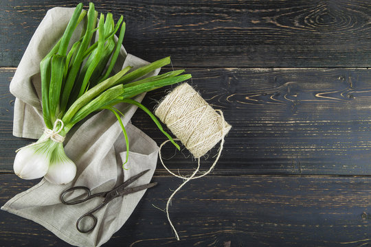Cebollas de primavera o cebolletas tiernas en un manojo sobre un fondo de madera 