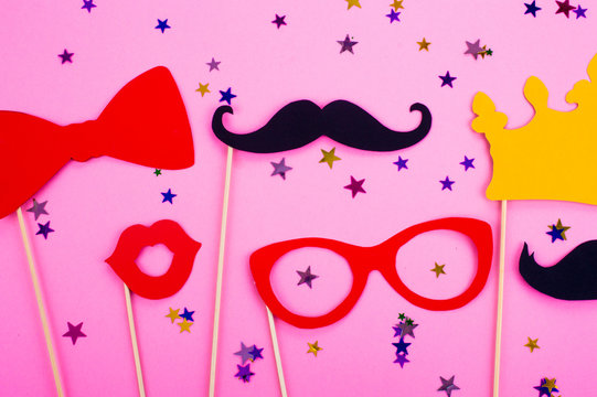 Photo booth props glasses, mustache, crown, lips on a pink background flat lay. Birthday parties and weddings.