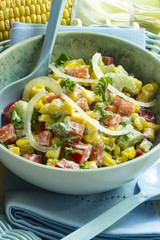 Maissalat mit Paprika, Stangensellerie und Tomaten in einer Salatschale mit Salatbesteck