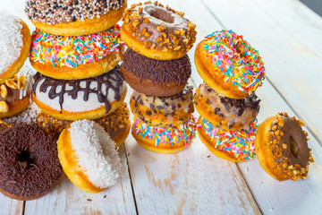 Collection of tasty donuts on white wooden board