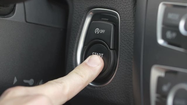 Car driver starting the engine by pressing the start and stop button in a modern car