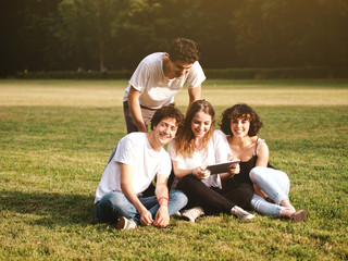 large group of friends together in a park using a tablet