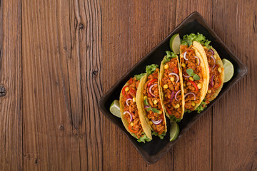 Tacos with meat and vegetables on wooden board