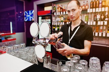 Barman hold bottle and pouring cocktail at the bar