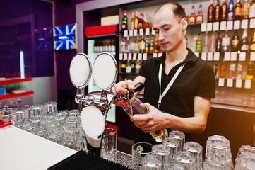 Barman hold bottle and pouring cocktail at the bar