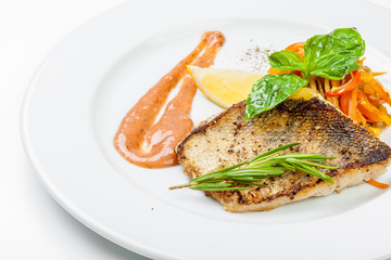 Dish of fish fillet with basil and lemon on plate isolated on white