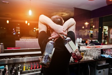 Barman hold bottle and pouring cocktail at the bar
