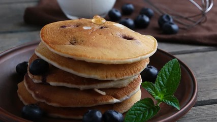 Blueberry pancakes on a plate pour maple syrup