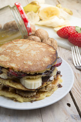 pancakes with banana, nuts and strawberry on wooden background