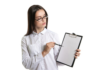 Young beautiful woman with a clipboard in his hands. Long-haired brunette in glasses and a white shirt. The woman points to the clipboard.