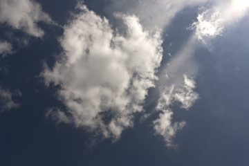 White clouds and dark blue sky with sunlight.