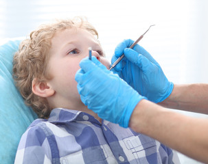 Doctor examining a child patient teeth by  orthodontic tools.
