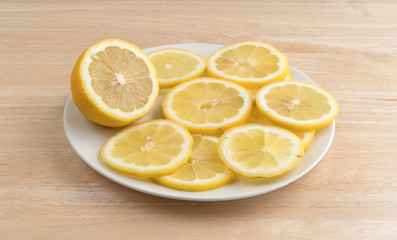 Lemon slices on a plate atop a wood cutting board.
