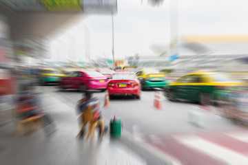 Traffic in the parking lot for taxis carry passengers inside the departure hall of the the airport is very busy because of the holiday; blurred zoom effect filter.
