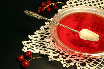 Red currant jelly in glass bowl against black background