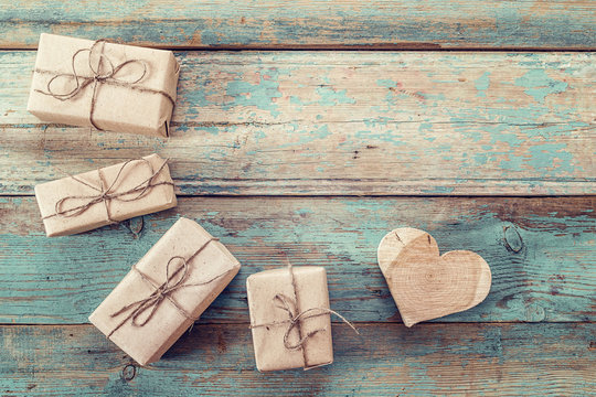 Gift parcels and carved wooden heart on a background of old boar