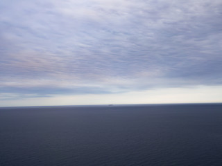Fototapeta premium Paisaje minimalista de colores azules con un barco al fondo en el horizonte, viajando por España en verano de 2016