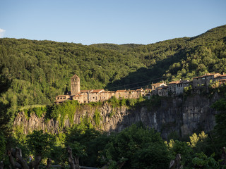 Fototapeta premium Vista del pueblo en el acantilado llamado Castellfollit de la Roca enmedio de la naturaleza verde dibujando una línea entre los árboles , viajando por España en verano de 2016