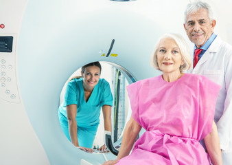 Obraz premium Woman in 60s ready to undergo MRi scan, assisted by two reassuri