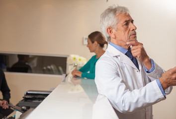 Mature male doctor analyzing x-ray test, doctor and assistant in