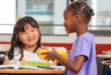 Two young multiracial african asian girls smiling at classroom d