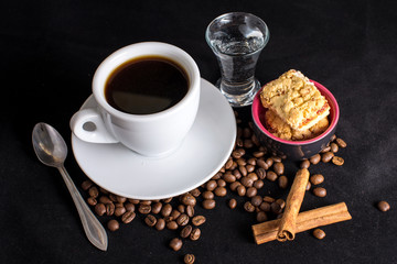 Cup of black coffee with biscuits, cinnamon, dark backdrop
